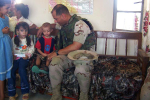 Luis Hernandez, assistant band director
Major Hernandez reads a book in English to an Iraqi child, who told the story back to Hernandez in Farsi, at an elementary school in Diwaniyah, Iraq. “I really missed my own kids after that day was over,” Hernandez said. Hernandez was part of the 413th Civil Affairs Battalion and assessed and rebuilt schools, roads, medical clinics, water treatment facilities and hospitals while in central and southern Iraq. Hernandez served for 24 years in the Army Reserve and is a Veteran of Desert Storm and Iraqi Freedom. 
