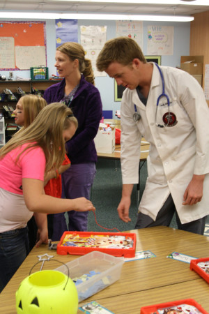 Giving instructions, senior Michael Ammons helps a kid play operation. At the Lakeview Elementary Fall Festival, HOSA members volunteered their time to play operation and pass out candy.
