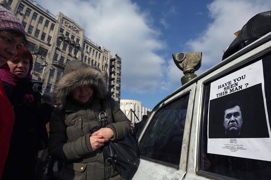The interim government of Ukraine put their deposed President Viktor Yanukovich on a wanted list Monday, Feb. 24, 2014. Women in Khreshchatik street look at an image of Yanukovich. (Sergei L. Loiko/Los Angeles Times/MCT)