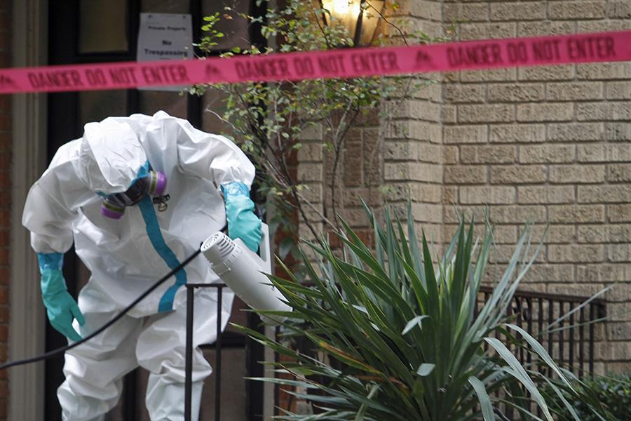 A worker with CG Environmental-Cleaning Guys sprays disinfectant outside the Marquita Street apartment building where a health care worker believed to be infected with Ebola lives on Sunday, Oct. 12, 2014 in Dallas. (Jim Tuttle/The Dallas Morning News/MCT)
