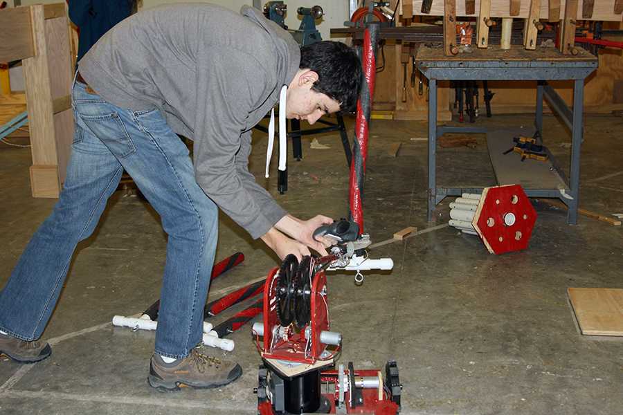 Kolton Burkhalter, senior and president of the CHS Robotics Club, uses the remote control to adjust the robot.