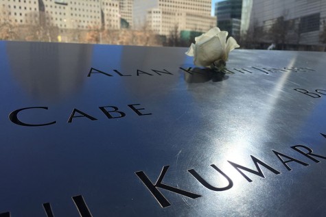 A single rose sits on a name engraved on one of the reflecting pools outside the museum.