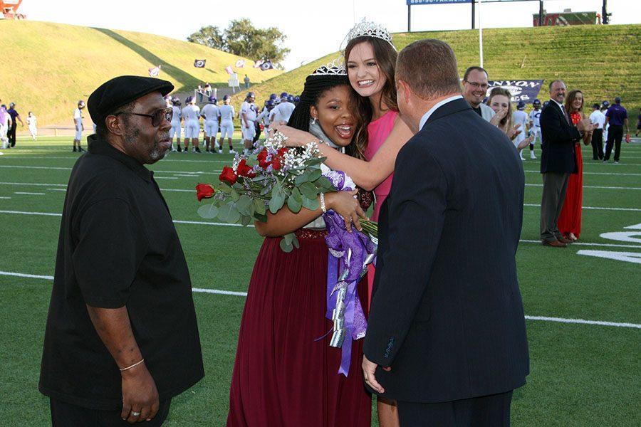 Homecoming queen Daisha Ferrell, accompanied by her grandfather Jimmy Robinson, is congratulated by last years queen, Calista Winings  and Principal Tim Gilliland.