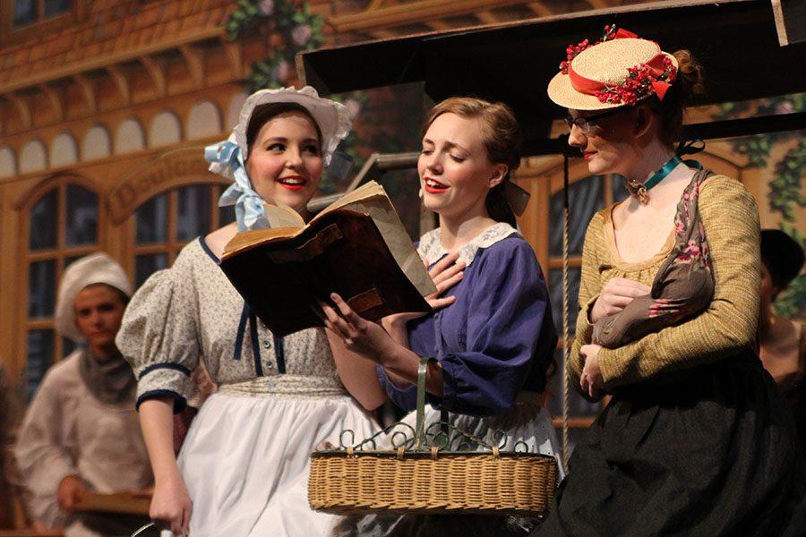 Belle, played by senior Madeleine Farren, shares her love of reading with village women played by sophomore Taryn Glenn and junior Charity Levens. 