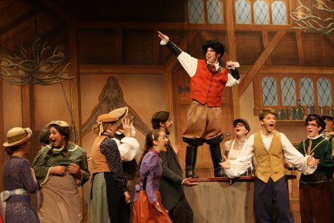 While playing Gaston, junior Josiah Dye flexes on top of a table for the taverne people.