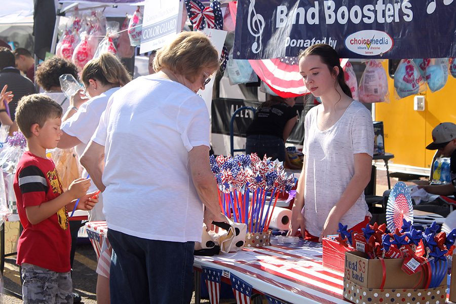 Freshman Zoe Kizziar assists customers at a booth during the July 4 Fair on the Square.