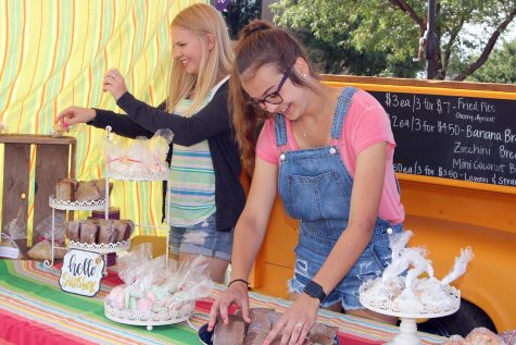 Graduate Emma Irlbeck and senior Maggie Bell arrange baked goods at their farmers market booth Saturday, Aug. 11.