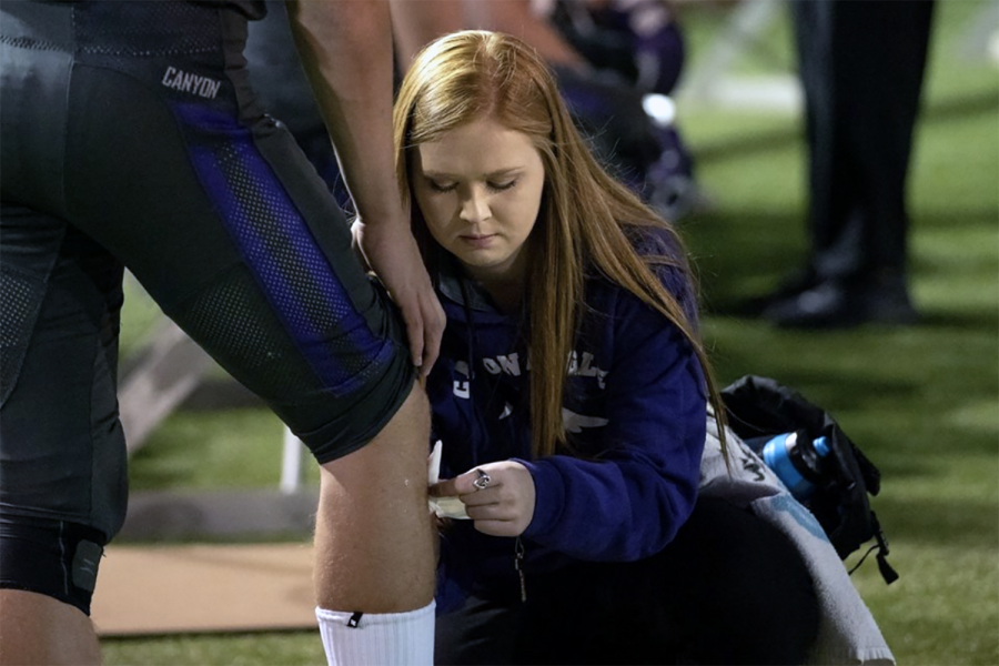Senior Jescelin Hardy bandages a player during a football game.