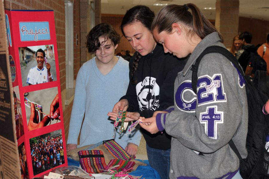 Spanish club members Emily Winters and Carly Behrens show Kelsey Braudt some of the pulseras available for purchase at the Spanish Clubs booth during lunch.