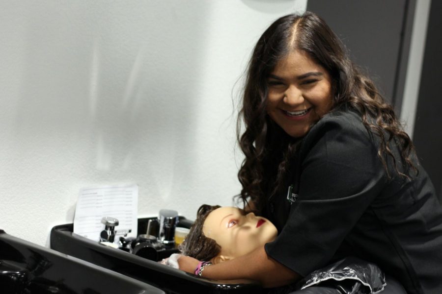 Junior Dezaray Hernandez practices a sanitization procedure of washing hair on a mannequin for Cosmetology.