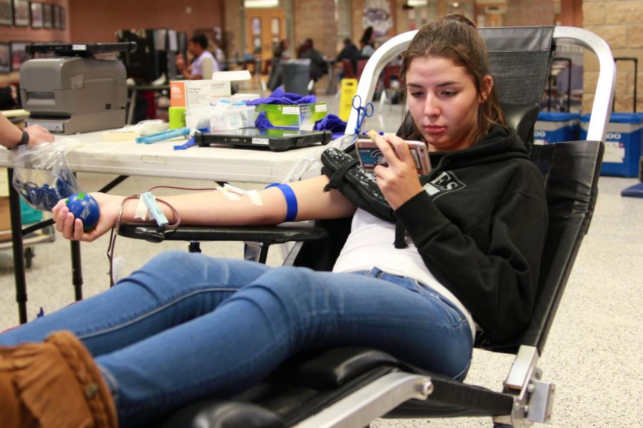Senior Raven Trevathan watches something on her phone while donating blood during the Vein Drain Blood Drive in October.