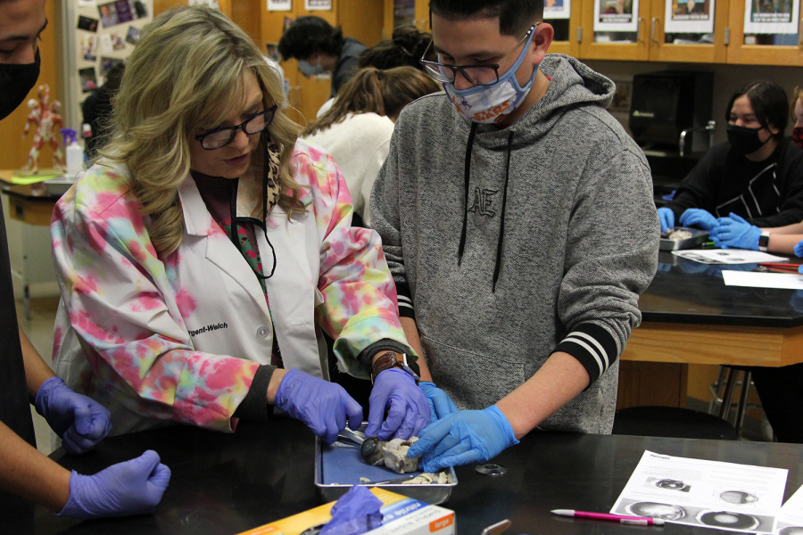 As a part of a lab in anatomy and physiology in sixth period, teacher Cortney Shaller demonstrates making the initial incision of a cows eye to junior Diego Sanchez Thursday, Jan. 21. Dissection allows the student to have a hands-on experience and allows them to physically touch and observe the different organs, Shaller said. This experience allows students to observe how form and function work hand in hand. This gives them a better understanding of their own bodies.
