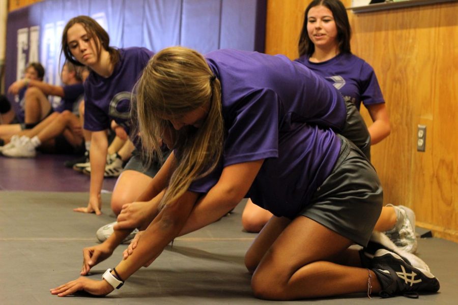 Sophomore Hannah Shepherd, left, and junior Aaralyn Adame, right, watch as sophomore Kylie Flores tackles freshman Alizae Reveles in wrestling practice. After the Canyon ISD school board approved the proposal in May, Canyon High School is now offering a girls wrestling program beginning this school year. The program is also being welcomed to the CISD  junior high campuses. “Once we started the boys program, we always knew the girls program was coming,” Frausto said. “We couldn’t be more excited to get this program up and running.” 