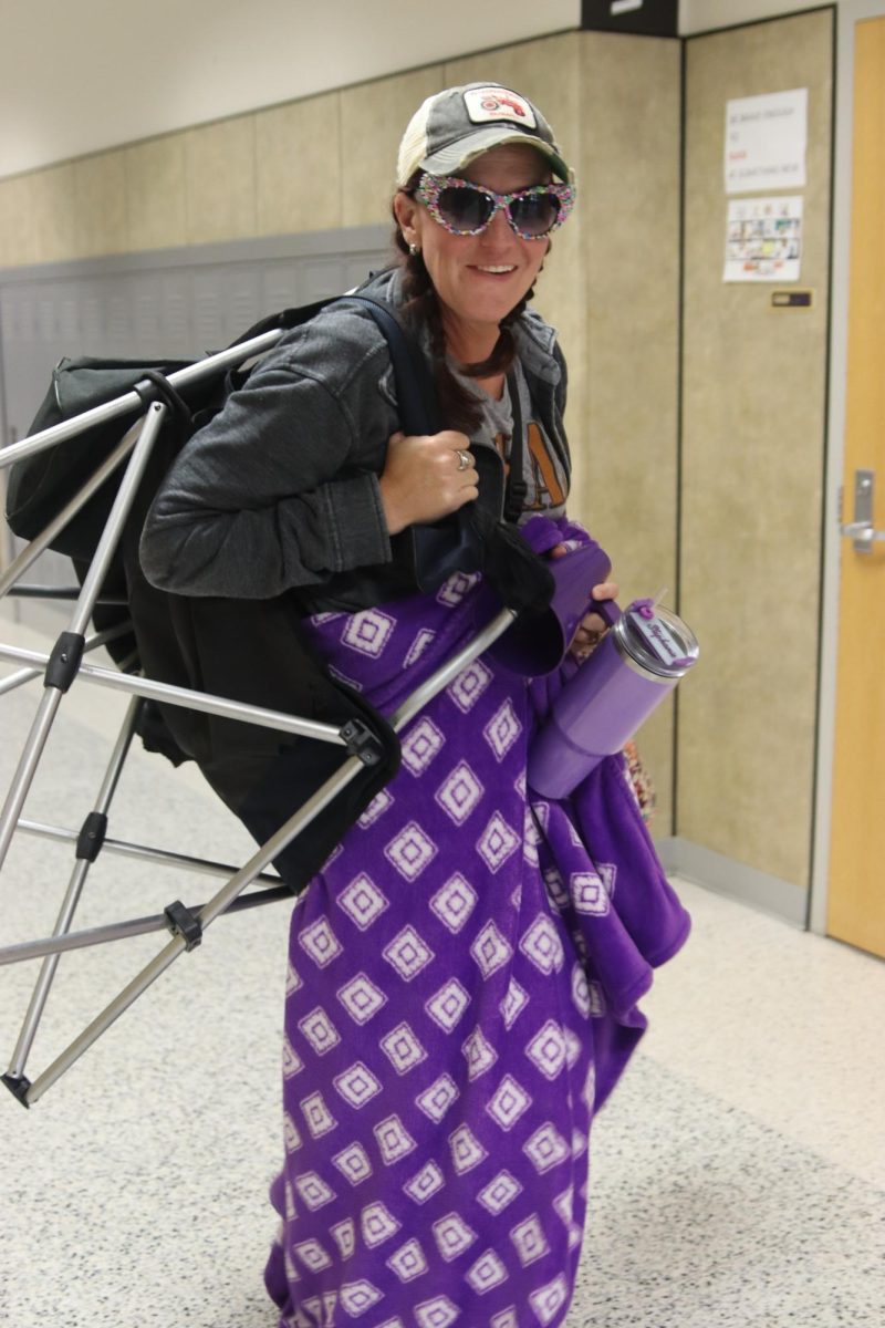 Teacher Stephanie Bass participates in the the Soccer Mom vs. BBQ Dad dress up day. To truly look the part she brought with her a foldable chair, a blanket, a Stanley, a yelling cone, a Lulemon crossbody, a cap, and some sunglasses. Bass said the inspiration for her outfit came from herself. Ive been a soccer mom for twenty three years,  Bass said. Ive probably spent ten thousand hours out on the baseball fields and tennis courts watching my kids play.
