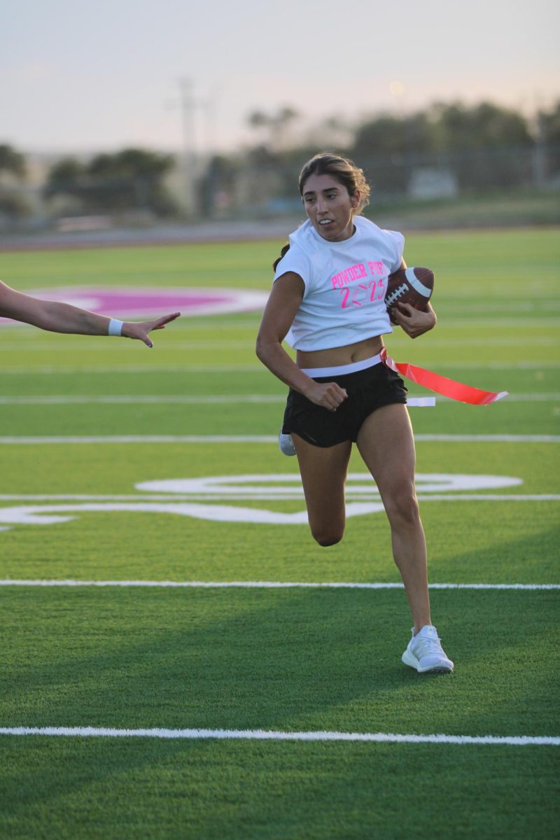 Senior Kamrin Guitierez runs the ball at the annual Powder Puff game after getting it from quarterback senior Mikaila Gilliland. This year the seniors and sophomores beat the juniors and freshmen. I signed up for Powder Puff because last year it was a lot of fun and I had a good time with all the girls, Guitierez said. I figured we were gonna win because seniors usually do and because the other team only had a few players.