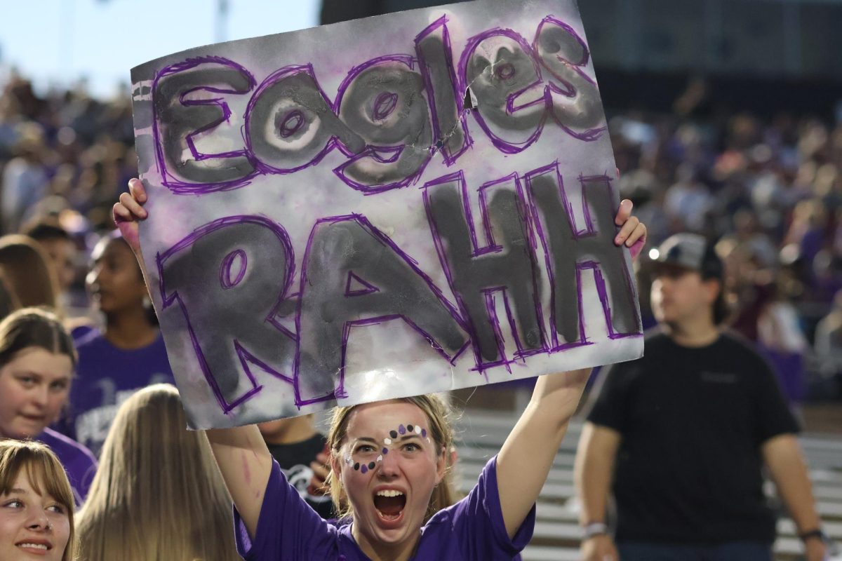 Junior Addie McCord screams for her team with her homemade sign that reads, Eagles RAHH. McCord decided to make a sign right before the game and used spray paint to decorate it. The reason I chose ‘Eagles RAHH’ is because it reminded me of how goofy my theatre friends are and I wanted my poster to be goofy, McCord said. Being in the student section is a lot of fun however, I think the theatre kids carry the energy and hype. It’s chaotic sitting with my theatre friends because most of the time we don’t know what’s going on, and our friends with minimal knowledge of football have to explain what’s happening.