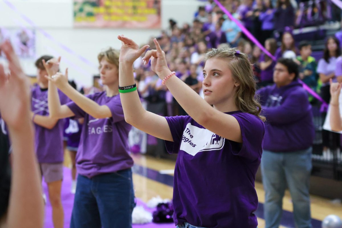 Junior Lexi Britten signs the National Anthem in the Homecoming Pep-Rally. Britten said her grandpa Brad helped her come up with her Purple-Out fit. I chose to participate because it is fun to dress up, Britten said. I enjoy picking the outfits and being creative with it.