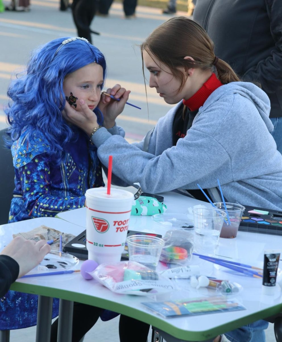 Junior Landri Bice paints a girls face at the 2023 Fall festival for ASL Honor Society.