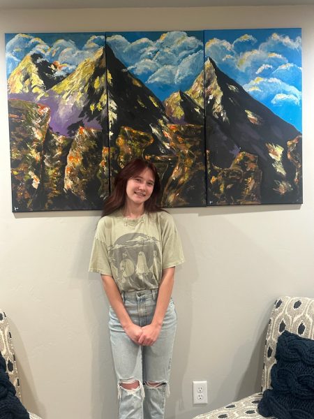 Sophmore Kaitlynn Hoggatt poses in front of her art. "I'll never be able to capture the complete meaning of God's presence on our earth, but I can try," Hoggatt said. "Even being able to catch a small amount of it is such a great feeling for me. I love doing it.”